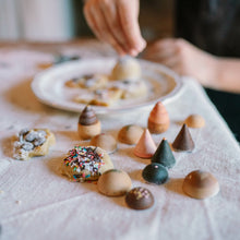 Load image into Gallery viewer, Children's hands arranging small cookies on a tablecloth.