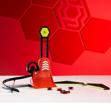 Load image into Gallery viewer, A red and black toy launcher or dart gun set with a yellow target on the front, displayed on a white surface against a red geometric background. Several small black and red darts are scattered in front.