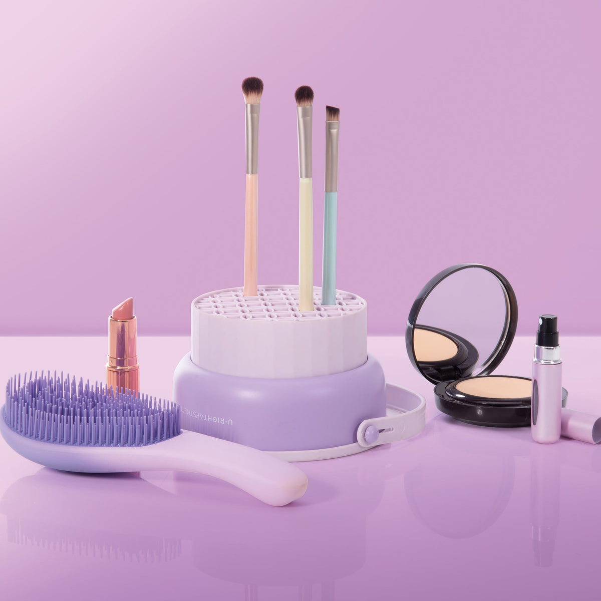 Makeup brushes and tools on a purple surface with a pink background