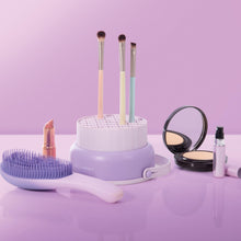 Load image into Gallery viewer, Makeup brushes and tools on a purple surface with a pink background
