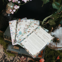 Load image into Gallery viewer, A styled flat-lay of printed cards or invitation sheets with vintage-style illustrations, arranged on stacked books surrounded by moss, flowers, a dark bottle, and small lights.