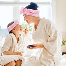 Load image into Gallery viewer, Woman and child in bathrobes with pink eye masks, sitting together in a bright room.