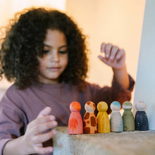 Load image into Gallery viewer, Child playing with colorful wooden peg dolls on a table.
