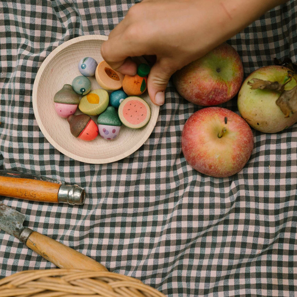 Colorful candies on a plate with apples and a knife on a checkered tablecloth