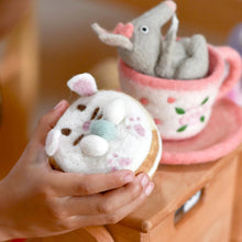 Load image into Gallery viewer, Hand holding a small plush toy with a background of a child playing with toys.
