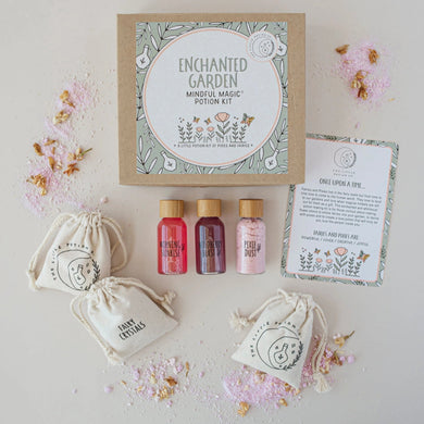 Set of small bottles, bags, and a circular product with 'Enchanted Garden' branding on a light background.