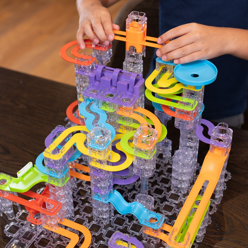 Colorful marble run toy set with clear base on a wooden surface