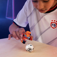 Load image into Gallery viewer, Child playing with a Foosbot near a soccer ball on a table with a dark background
