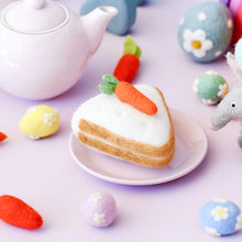 Load image into Gallery viewer, Pastel-colored cake-shaped cookie with a carrot on a plate, surrounded by decorative eggs and a teapot.
