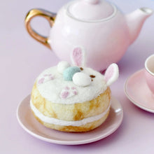 Load image into Gallery viewer, Donut with bunny ears on a pink plate with a teapot in the background
