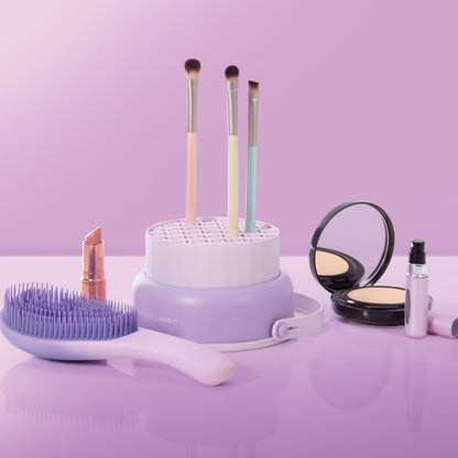 Makeup brushes and tools on a purple surface with a pink background