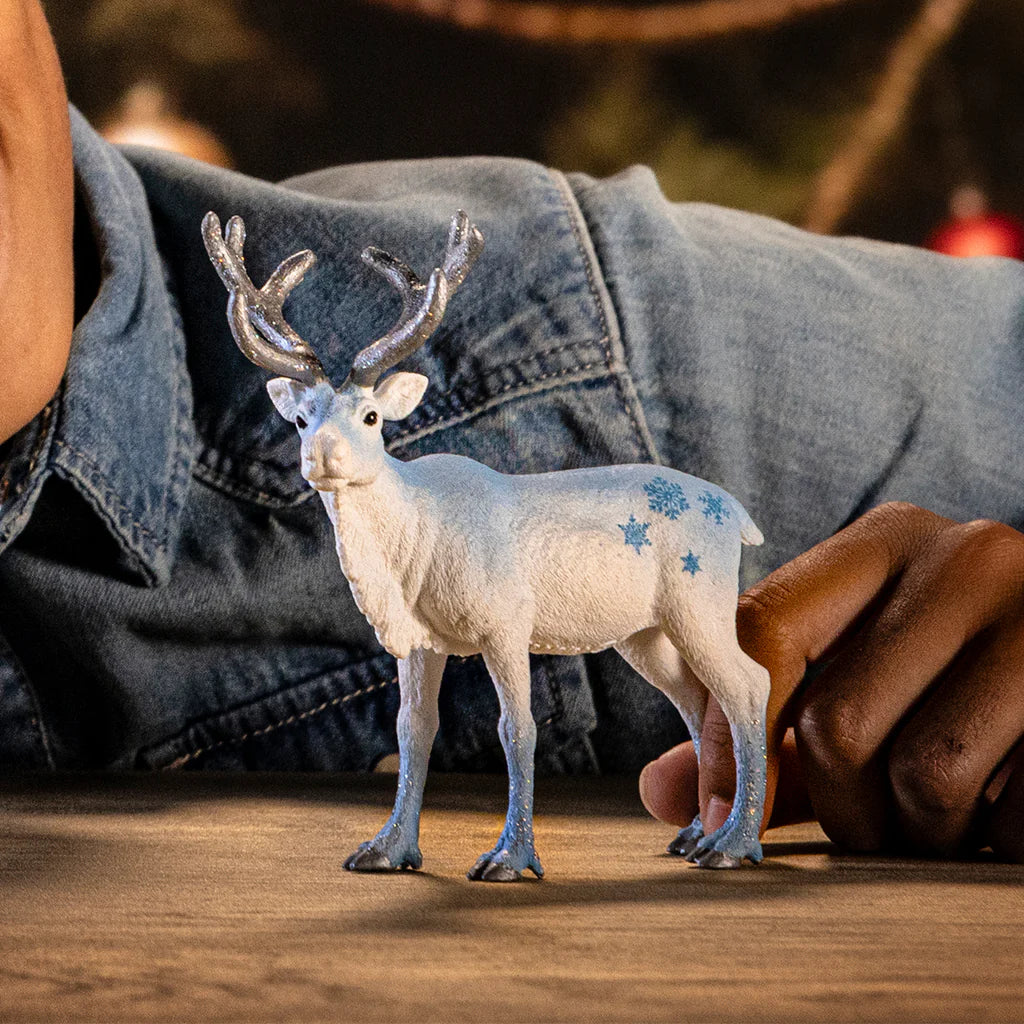 White deer figurine with blue spots on a wooden surface