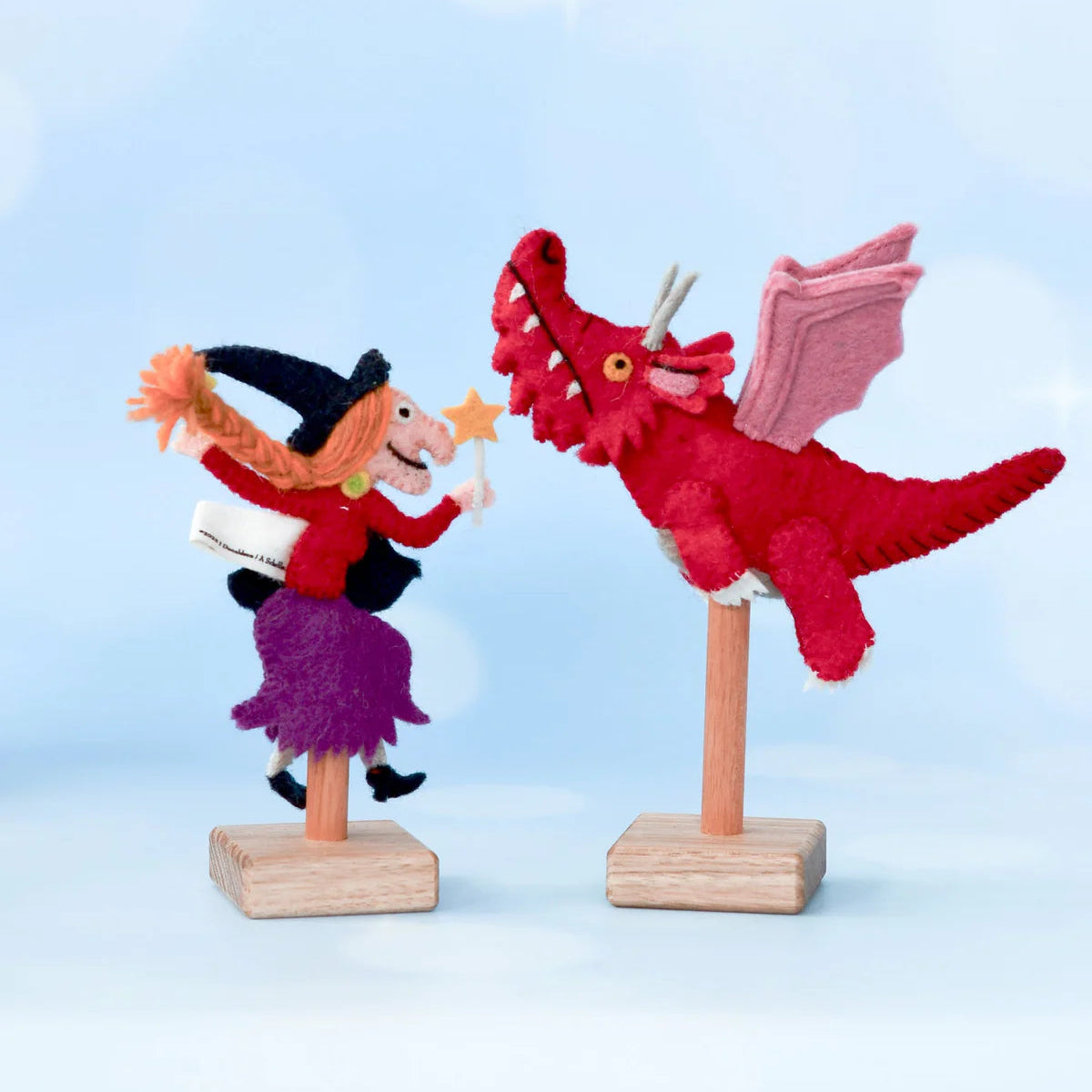 Decorative figure of a witch and a red dragon on stands against a light blue background