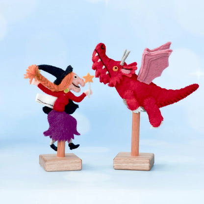 Decorative figure of a witch and a red dragon on stands against a light blue background