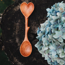 Load image into Gallery viewer, Wooden heart-shaped spoon on a dark surface with blue flowers.
